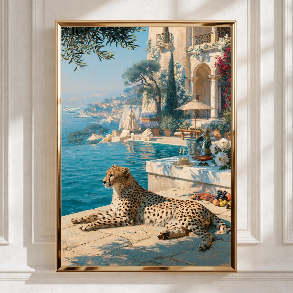 A framed vertical art print depicting a cheetah resting by a blue sea beside a luxurious coastal villa with a pool, displayed on a white paneled wall.